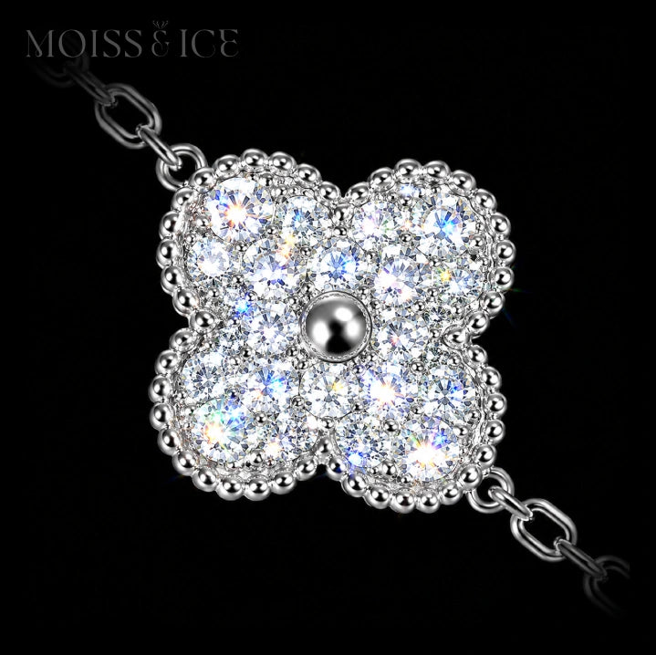 Close up of a moissanite 4 leaf clover bracelet with gold.