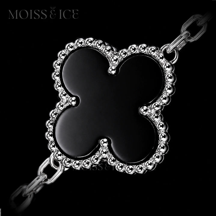 Close up of a black 4 leaf clover bracelet with gold.
