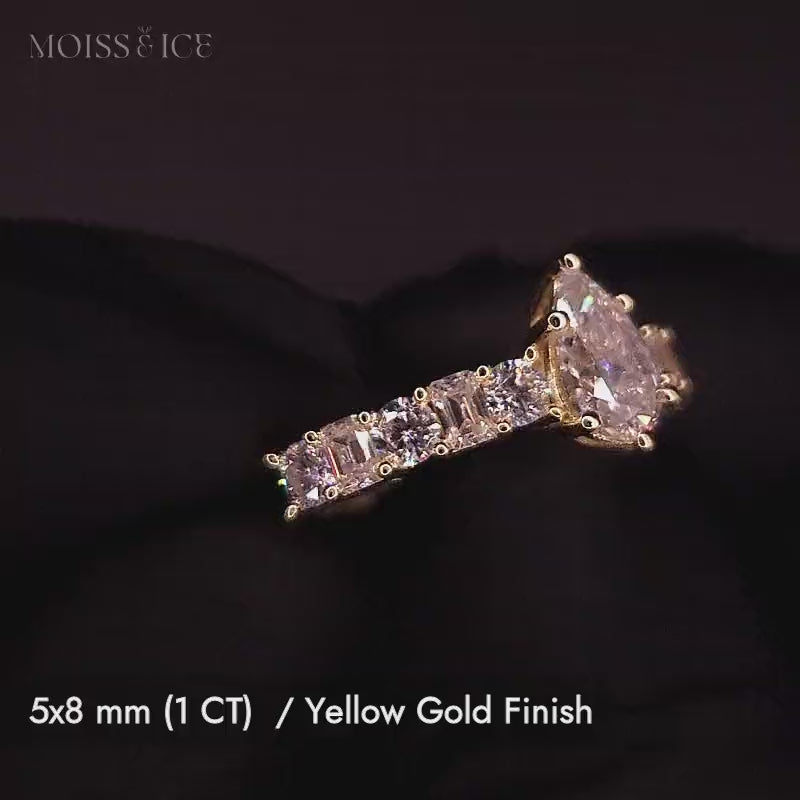 Close up pear cut Lab-Grown Diamond engagement ring with a pavé band of alternating baguette and round cut Lab-Grown Diamond stones in 14k and 18k gold